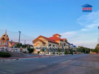 Exterior view of a spacious residential building with traditional style roofing and a paved courtyard