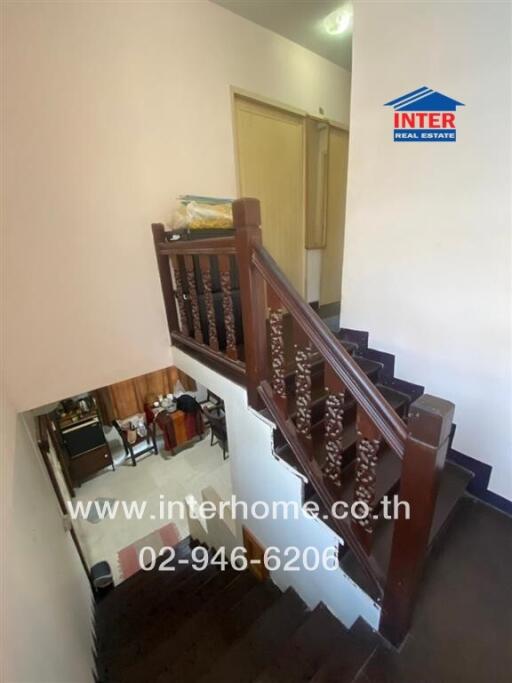 Interior view of a home showing staircase with wooden railing and a glimpse into the dining area