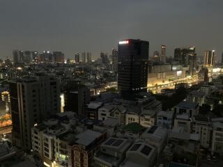 Nighttime cityscape view from high-rise building, showcasing urban skyline with illuminated buildings