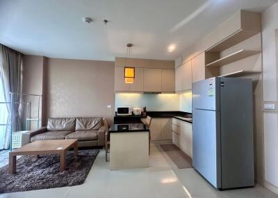 Spacious living area with modern kitchenette, including a comfortable sofa, wooden coffee table, and well-equipped kitchen with appliances