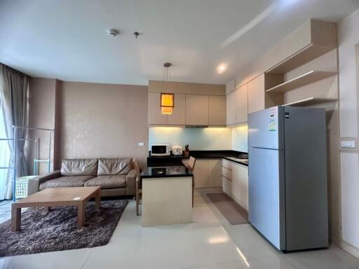 Spacious living area with modern kitchenette, including a comfortable sofa, wooden coffee table, and well-equipped kitchen with appliances