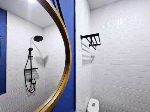 Modern bathroom with white tiles and blue walls, featuring a circular mirror and a walk-in shower