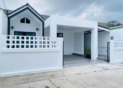 Modern white single-story house with covered parking and stylistic fence