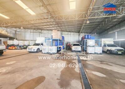 Spacious industrial warehouse interior with multiple vehicles and storage units