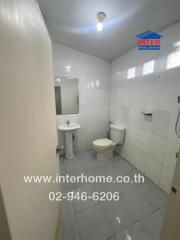 Compact white tiled bathroom with toilet and sink