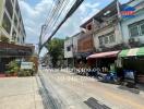 Street view of residential and commercial buildings with visible real estate banner