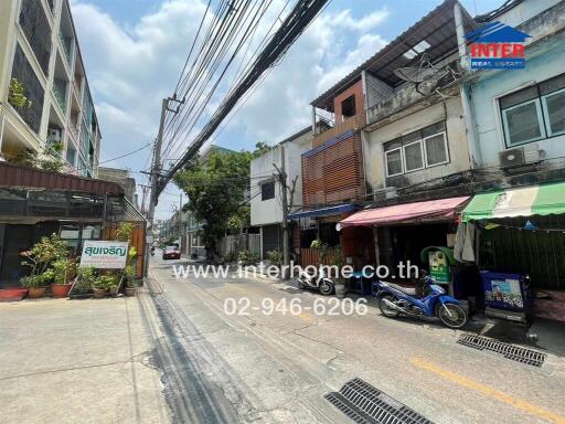 Street view of residential and commercial buildings with visible real estate banner