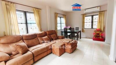 Spacious living room with large sofa and dining area