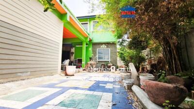 Colorful exterior of a two-story house with a vibrant garden and artistic tiles