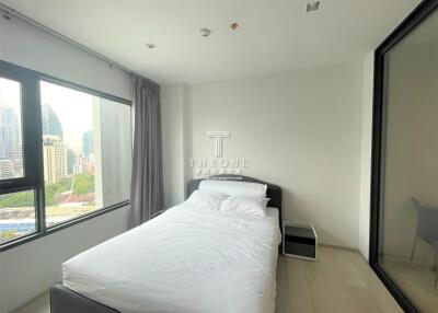 Modern bedroom with large window overlooking city skyline
