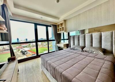Spacious modern bedroom with large window overlooking the city