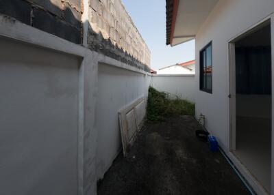 Side alley of a house showing wall, small garden area, and part of the house