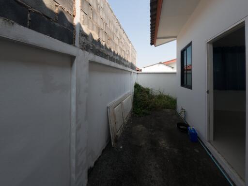 Side alley of a house showing wall, small garden area, and part of the house