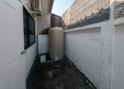 Narrow outdoor utility space with a large water tank and air conditioning unit