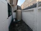 Narrow outdoor utility space with a large water tank and air conditioning unit