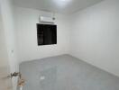 Spacious empty room with white walls and tiled flooring