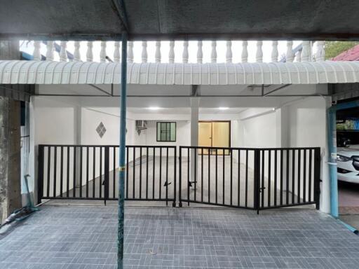 Covered residential garage with secured metal gate and tiled floor