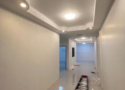 Modern home interior showing a long, bright hallway with glowing ceiling lights, glossy floor tiles, and a step ladder