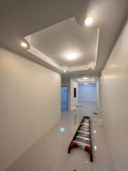 Modern home interior showing a long, bright hallway with glowing ceiling lights, glossy floor tiles, and a step ladder