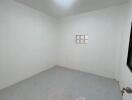 Small empty bedroom with white walls and tiled floor
