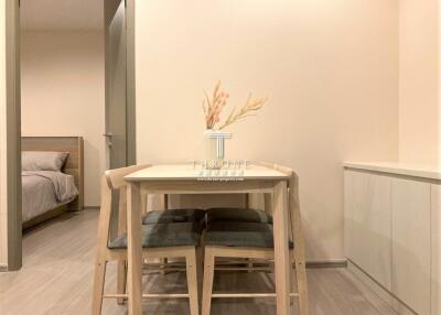 Modern dining area with minimalist wooden table and two chairs, adjacent to a cozy bedroom