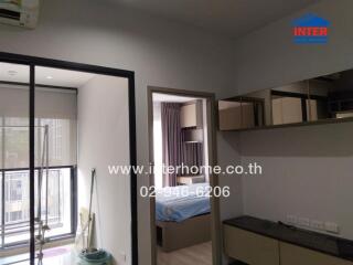 Interior view of a modern apartment featuring a kitchenette and a glimpse into the bedroom