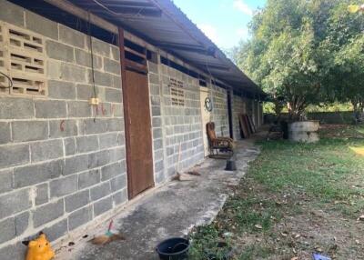 Exterior view of a rustic building with multiple doors and a chair outside