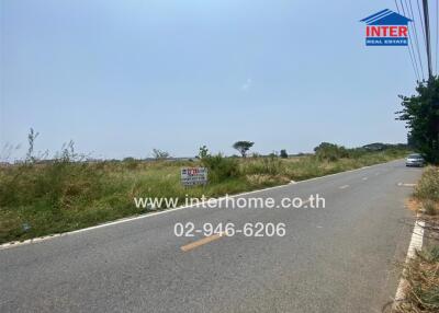 Empty plot of land available for sale along a roadside with clear signage