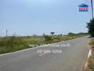 Empty plot of land available for sale along a roadside with clear signage