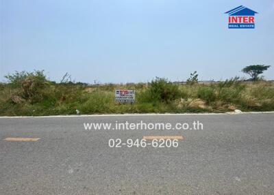 Empty land for sale with clear sky and roadside view