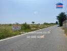 Wide street view with real estate signs and a clear sky