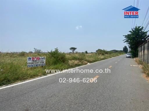 Wide street view with real estate signs and a clear sky