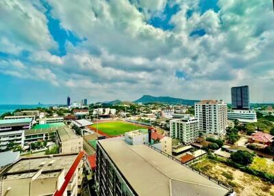 Panoramic city view with clear sky, buildings and a sports field