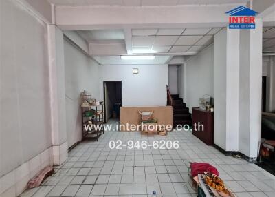 Spacious living room with white tiles and staircase