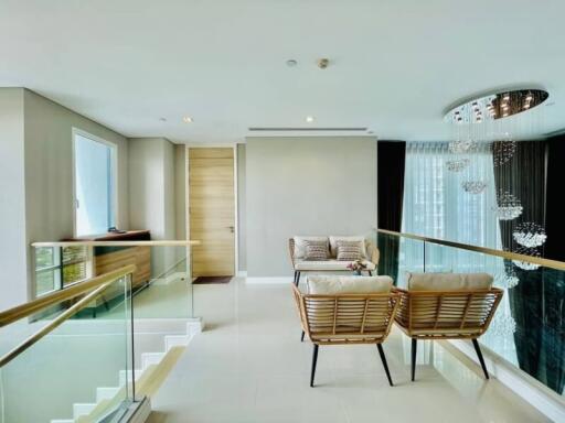 Modern living room with stairs, balcony, and elegant chandelier