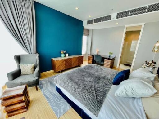 Spacious bedroom with modern decor, featuring a large bed and vibrant blue accent wall