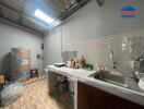 Compact kitchen with stainless steel sink and storage area