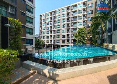 Modern residential building complex with large swimming pool and landscaped garden