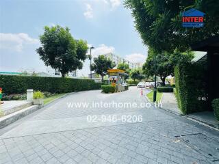 Well-maintained entrance of a residential complex with lush greenery