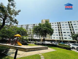 Exterior view of a residential apartment complex with playground and parking