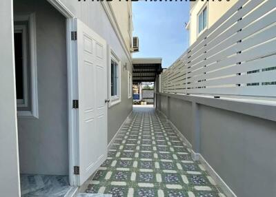 Narrow alleyway between residential buildings with patterned walkway and exterior doors