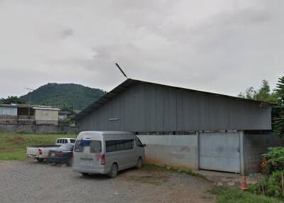 Exterior view of a large industrial building with vehicles parked outside