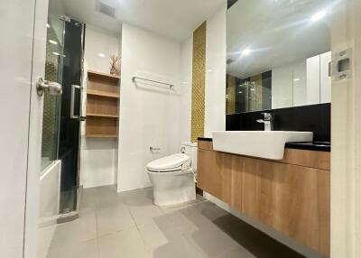Modern bathroom with sleek design, featuring wooden cabinets and a spacious shower area