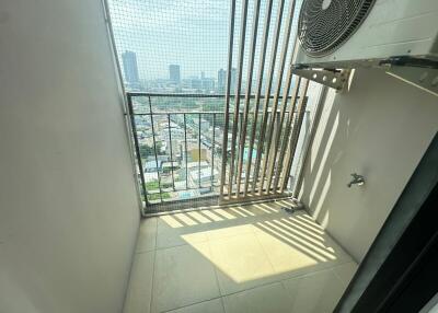 High-rise apartment balcony overlooking cityscape with safety grill and air conditioning unit