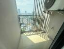 High-rise apartment balcony overlooking cityscape with safety grill and air conditioning unit
