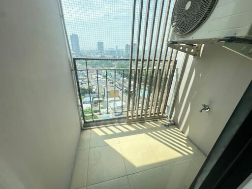 High-rise apartment balcony overlooking cityscape with safety grill and air conditioning unit