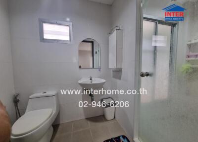 Modern bathroom interior with white walls, a toilet, sink, and glass shower enclosure