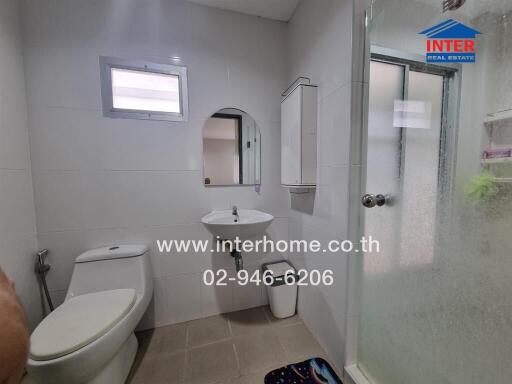 Modern bathroom interior with white walls, a toilet, sink, and glass shower enclosure