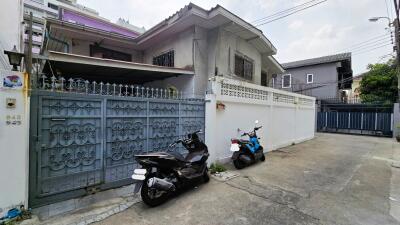 Exterior view of the house with gated entrance and two parked scooters