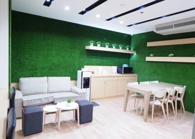 Modern living room with green accent wall and integrated kitchen